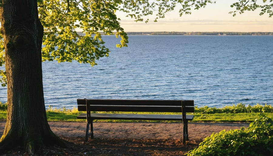 Dramatic sunset over Lake Ontario with silhouetted park benches along the trail